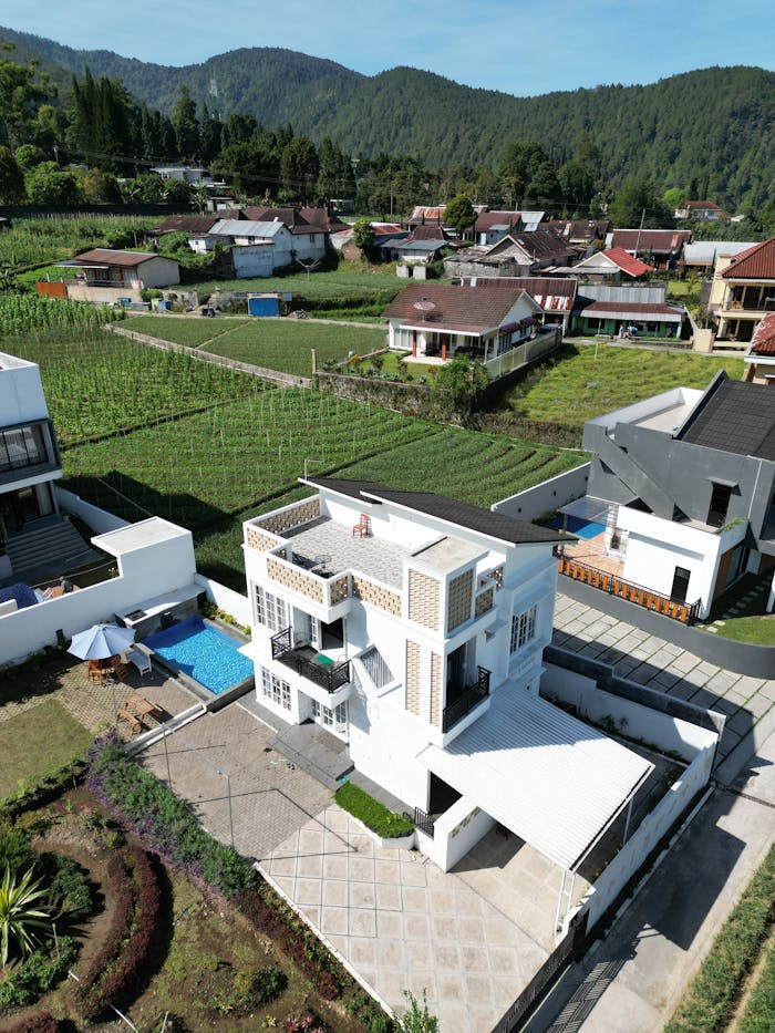 service-01 Aerial shot of a modern house surrounded by lush greenery and hills.