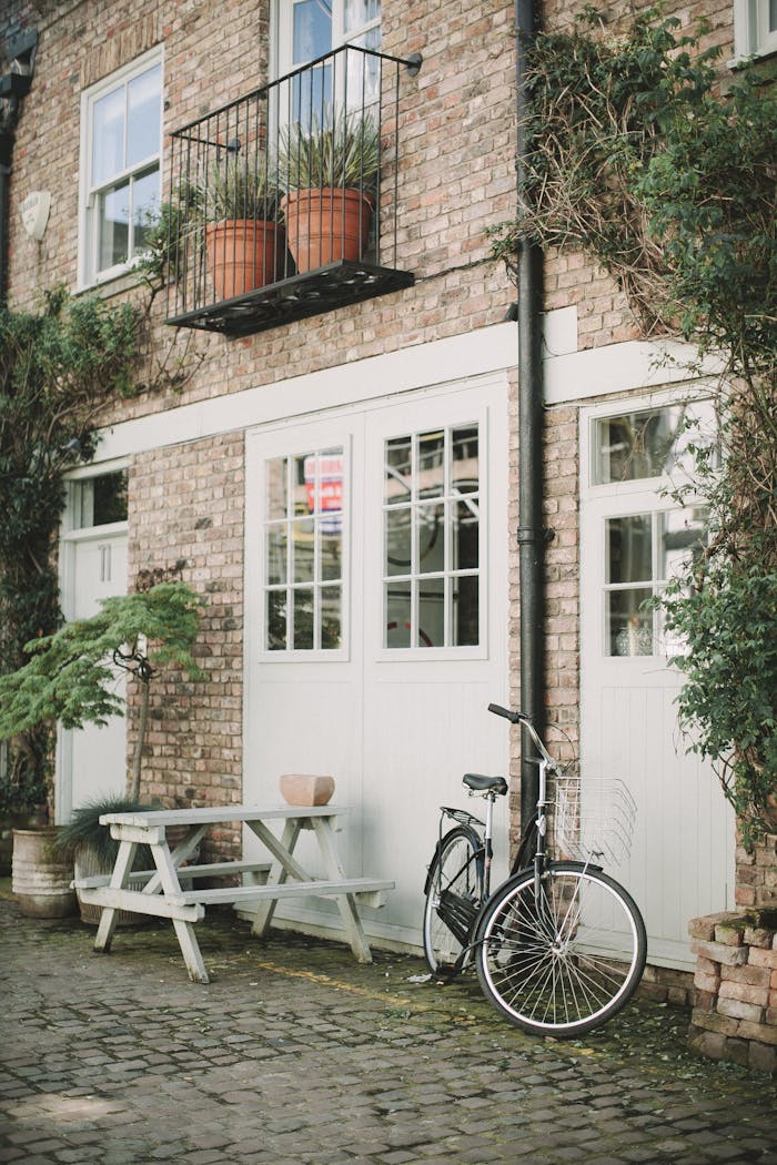 our-mission Quaint brick building exterior in London with bicycle and potted plants.