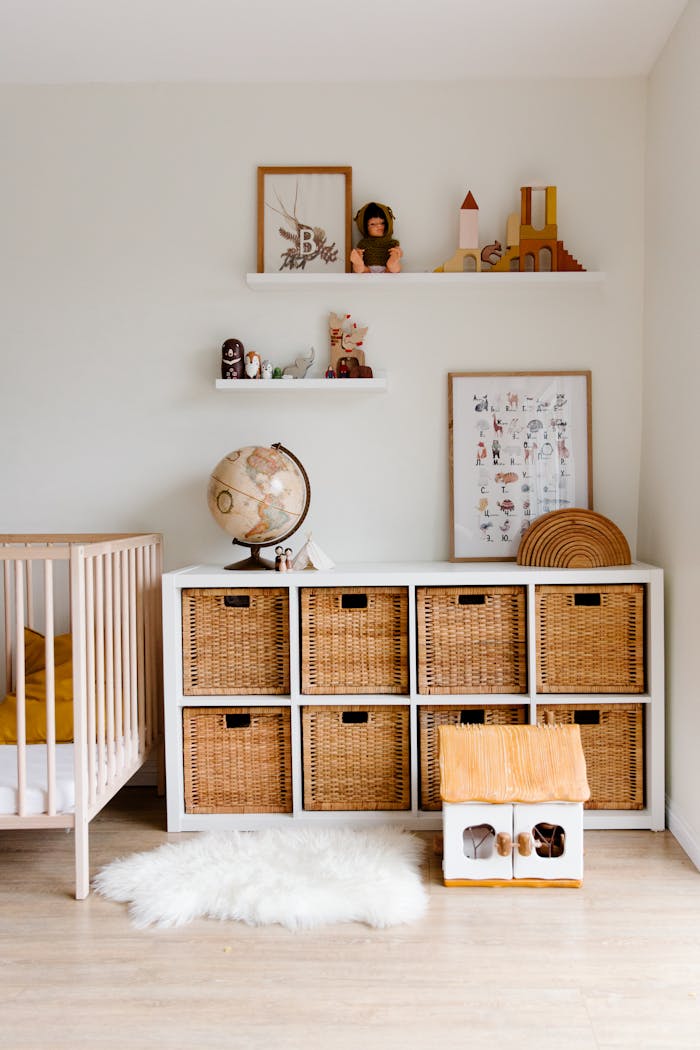 service-05 Comfortable bed with toys globe and paintings placed on wooden cabinet with wicker boxes and soft white rug with toy house on floor