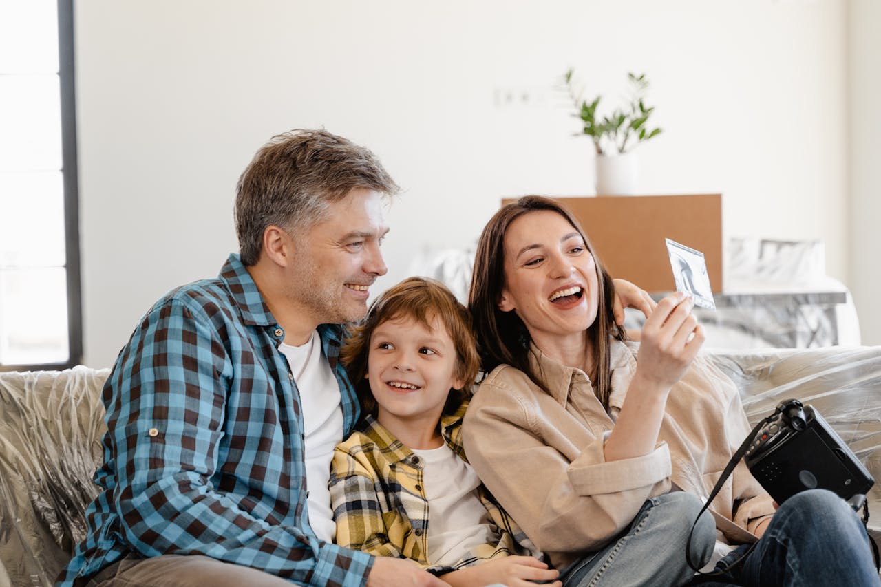 service-02 A cheerful family enjoys time together on a couch surrounded by moving boxes in their new home.