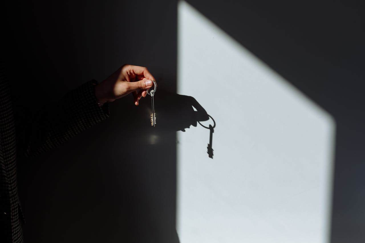 who-we-are Minimalist photo of a hand holding a key casting a shadow, signifying property ownership